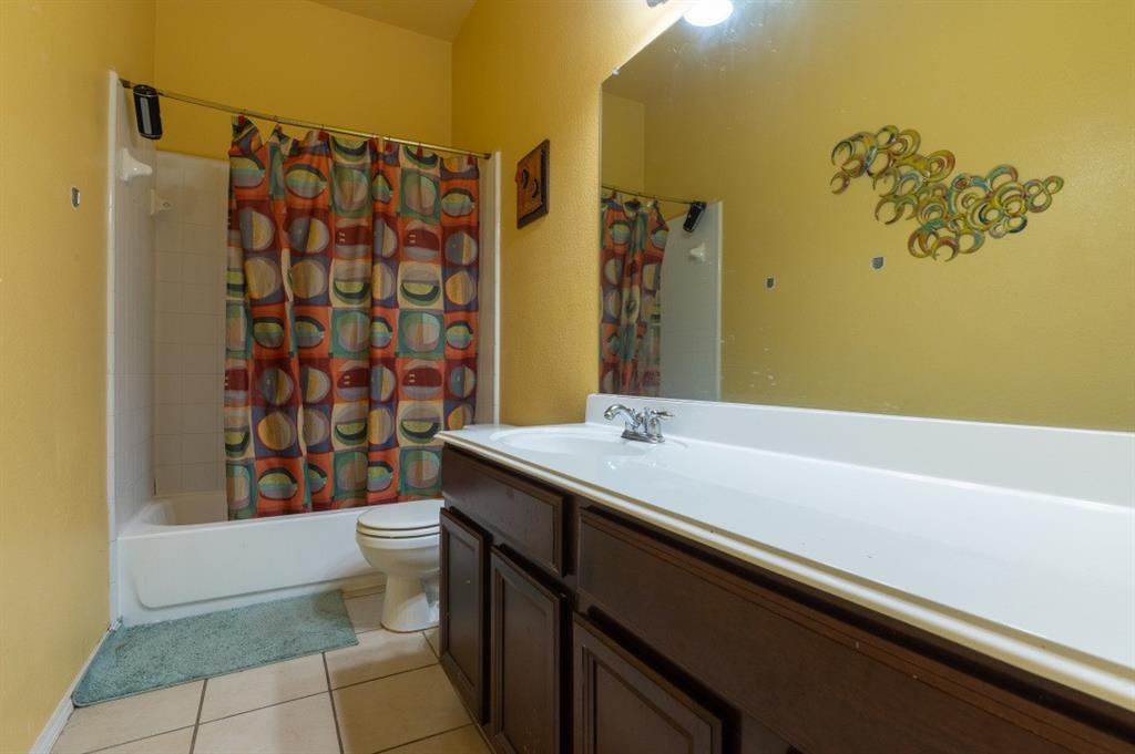 2248 Condor Street Grand Prairie, TX 75052 - Photo 10 of 25 a bathroom with a sink a toilet and shower curtain