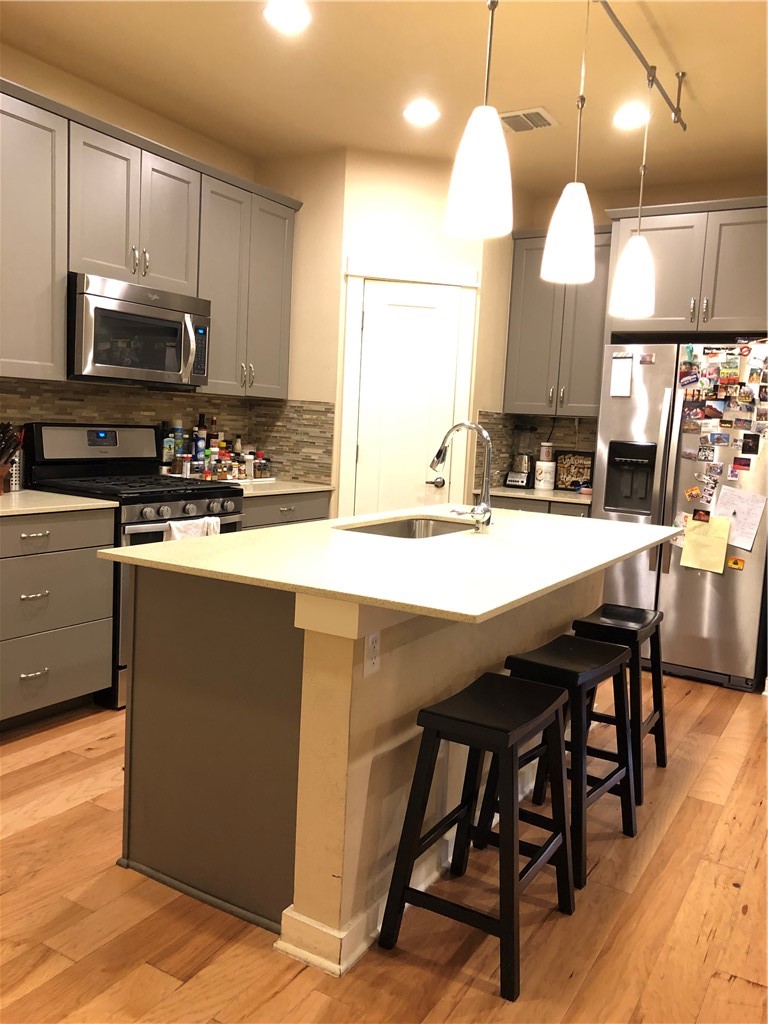 1303 Casey Street, Unit A Austin, TX 78745 - Photo 3 of 16 a kitchen with stainless steel appliances kitchen island granite countertop a sink a stove a dining table and chairs