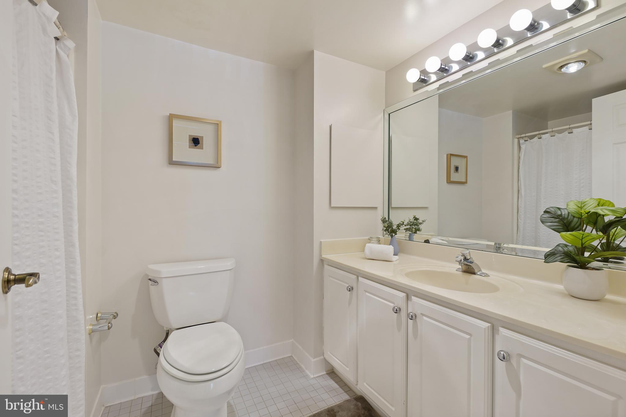 14801 Pennfield Circle, Unit 306 Silver Spring, MD 20906 - Photo 23 of 45 a bathroom with a toilet a sink and mirror