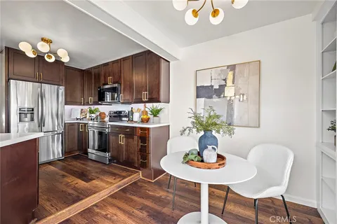 a kitchen with granite countertop stainless steel appliances a dining table and chairs