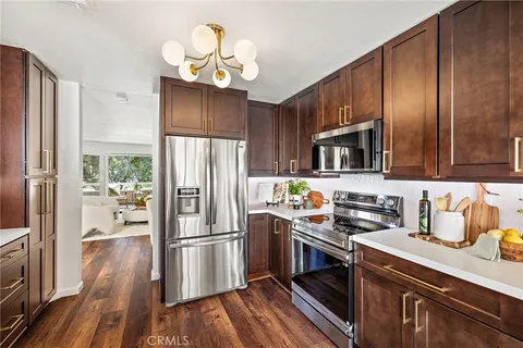 a kitchen with stainless steel appliances a refrigerator a stove a sink dishwasher and wooden cabinets with wooden floor