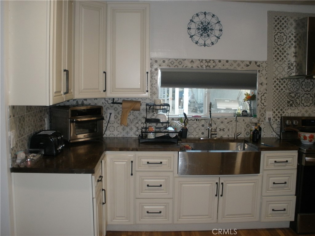 39036 Sage Road Lucerne Valley, CA 92356 - Photo 26 of 41 a kitchen with white cabinets and black appliances