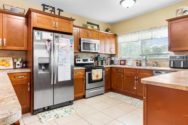 a kitchen with stainless steel appliances granite countertop a refrigerator a stove and a sink with wooden cabinets