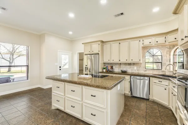 a kitchen with granite countertop a stove and white cabinets