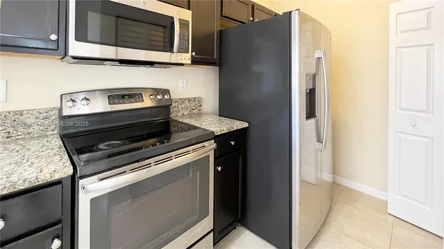 a kitchen with stainless steel appliances granite countertop a refrigerator stove and microwave