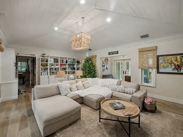 a living room with furniture potted plant and open kitchen view