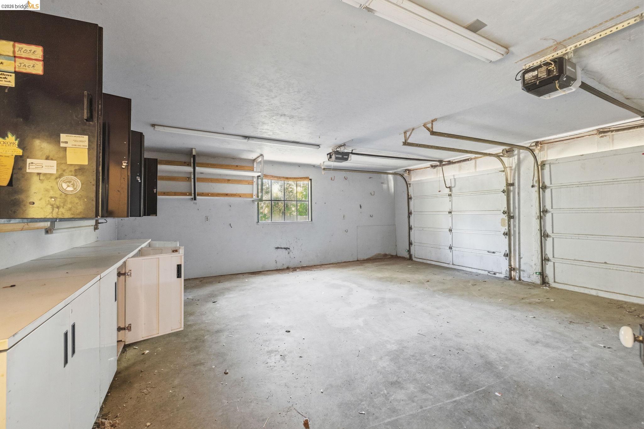 22401 South Fork Road Sonora, CA 95370 - Photo 19 of 34 Spacious garage featuring concrete flooring, two overhead garage doors, an integrated window, built-in cabinetry, and overhead fluorescent lighting