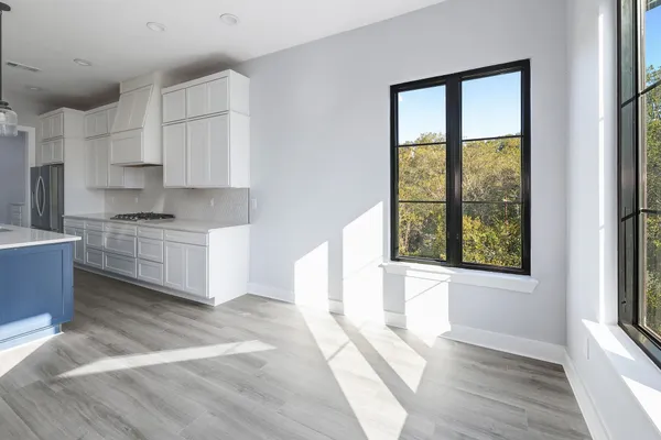a kitchen with stainless steel appliances cabinets a large window and a wooden floor