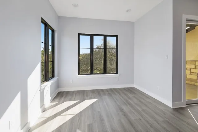 an empty room with wooden floor and windows