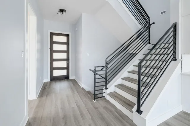 an entryway in a hall with wooden floor and a view of bathroom