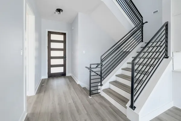 an entryway in a hall with wooden floor and a view of bathroom