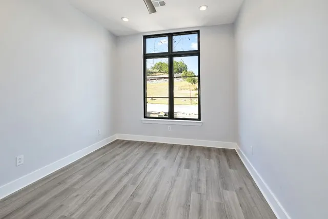 an empty room with wooden floor and windows