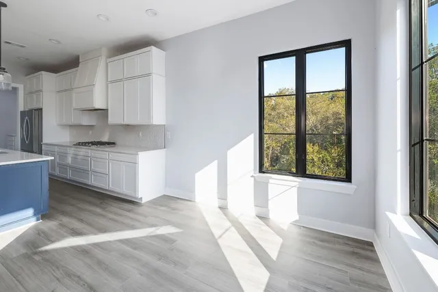 a kitchen with stainless steel appliances cabinets a large window and a wooden floor