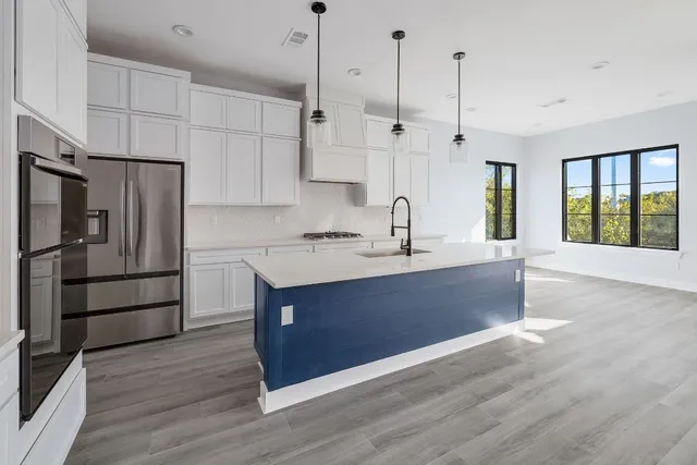 a kitchen with stainless steel appliances granite countertop a refrigerator a sink dishwasher a stove and a sink with wooden floor