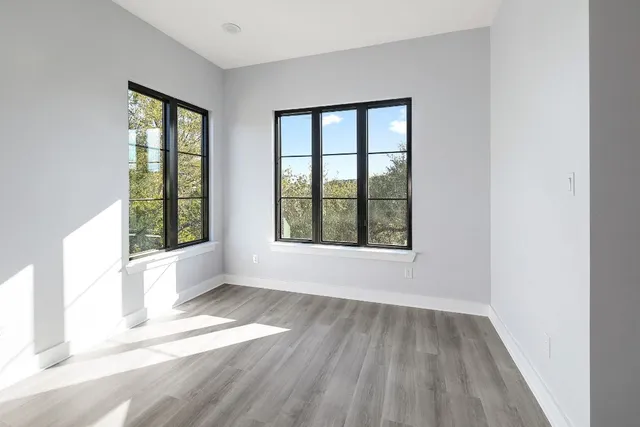 a view of an empty room with wooden floor and a window