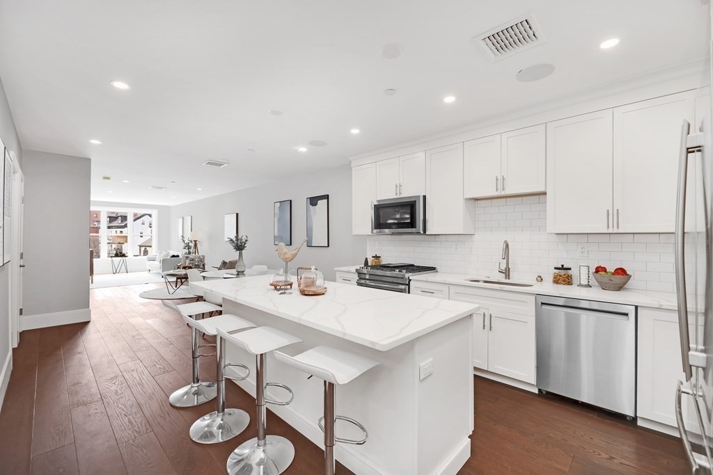 a kitchen with a sink a stove cabinets and wooden floor
