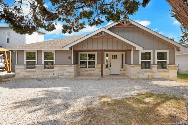 a view of a yard in front of a house with large windows