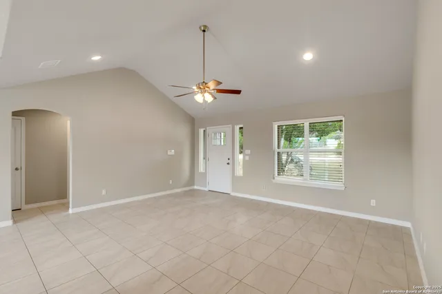 an empty room with ceiling fan and windows