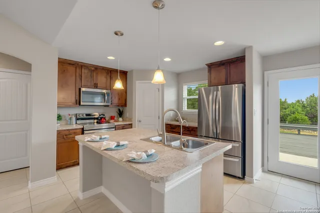 a kitchen with stainless steel appliances granite countertop a refrigerator a sink a stove a microwave and island