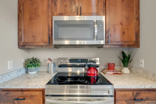 a large kitchen with kitchen island granite countertop a refrigerator a stove a oven a sink a counter top space and cabinets