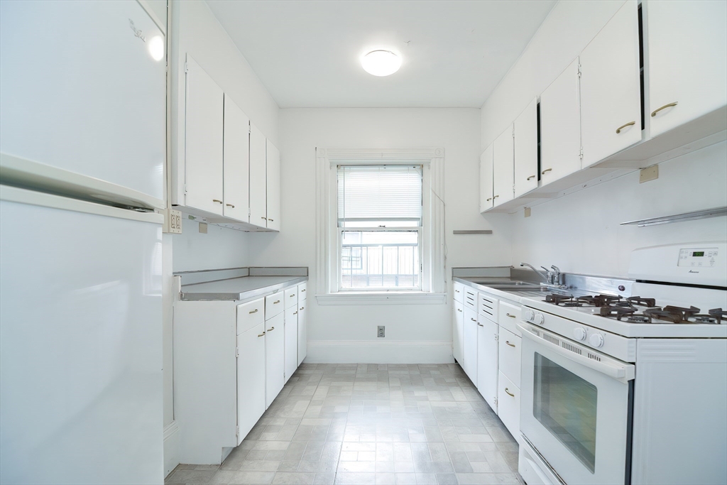 a kitchen with granite countertop a stove sink and cabinets