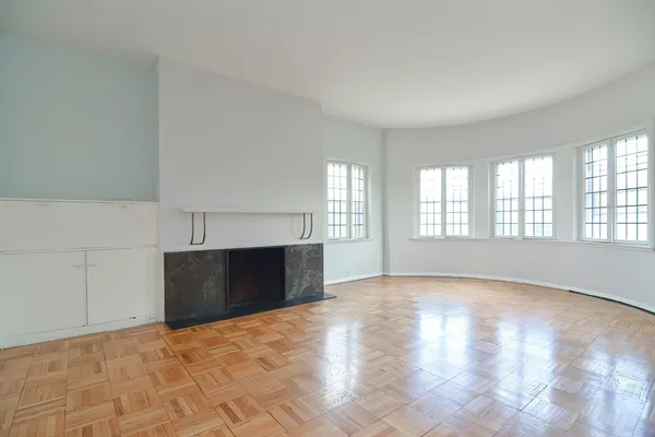 a view of an empty room with a window and fireplace
