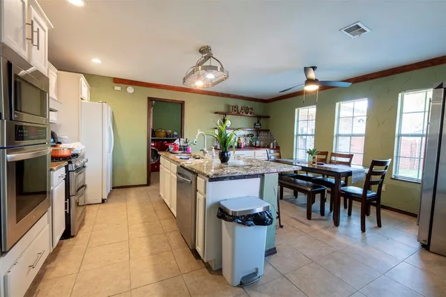 a kitchen with stainless steel appliances kitchen island granite countertop a table and chairs in it
