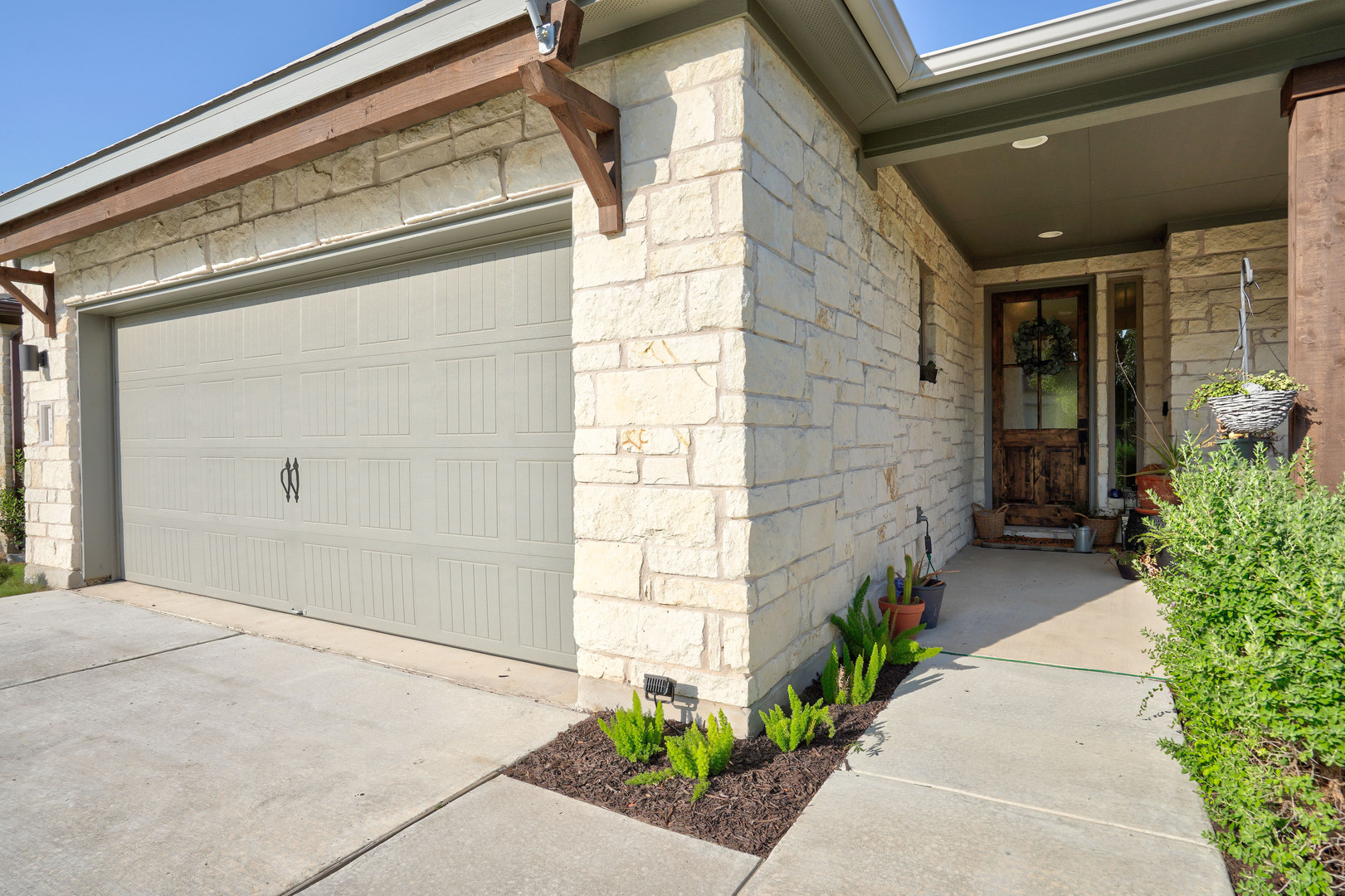 Stone veneer exterior featuring a two-car garage with a panel door, concrete driveway, and covered entry