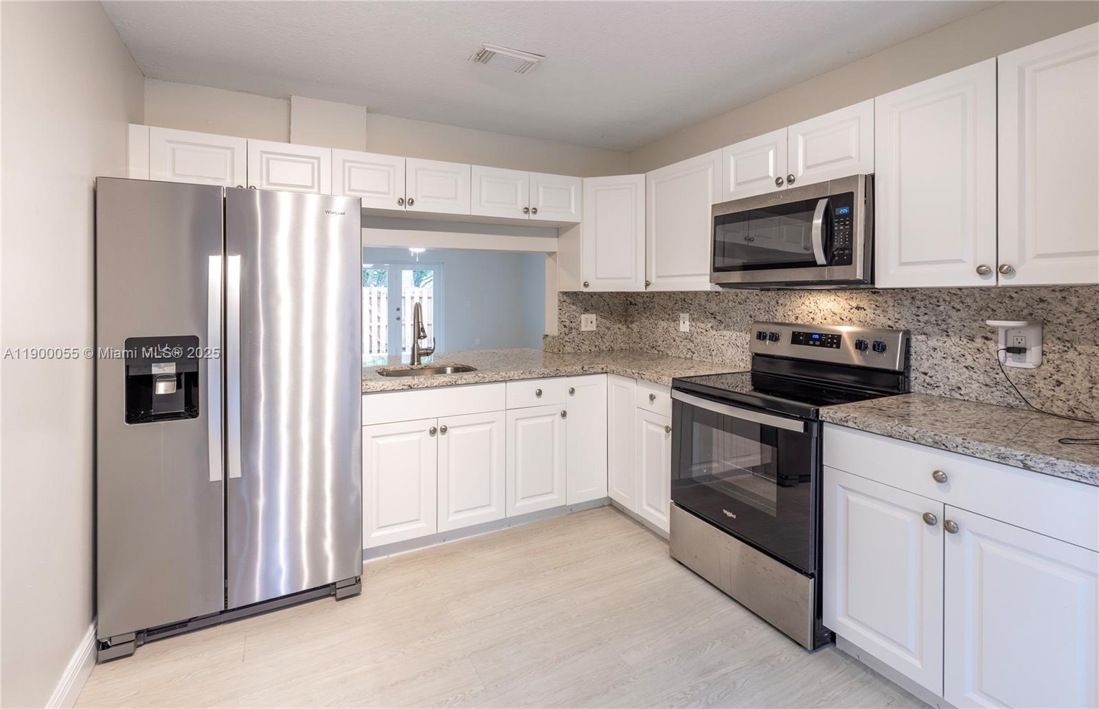 14237 Southwest 94th Cir Lane, Unit 101 Miami, FL 33186 - Photo 8 of 34 a kitchen with white cabinets and stainless steel appliances