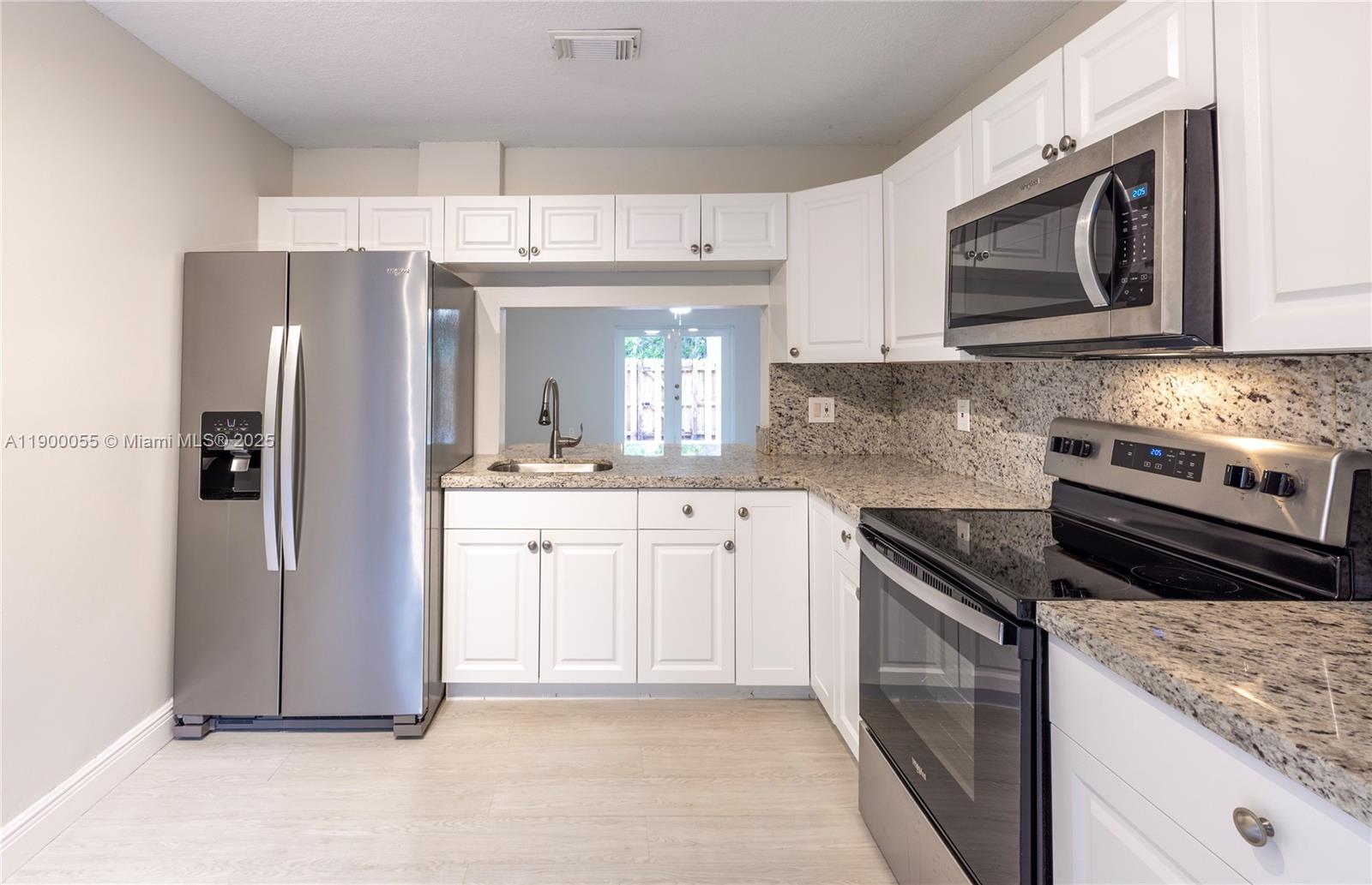 14237 Southwest 94th Cir Lane, Unit 101 Miami, FL 33186 - Photo 9 of 34 a kitchen with stainless steel appliances granite countertop a refrigerator stove and sink
