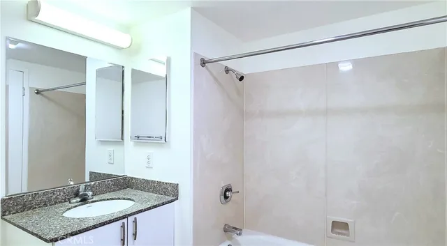 a bathroom with a granite countertop sink a mirror and a shower