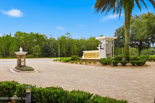 a sign board with flower plants and wooden fence