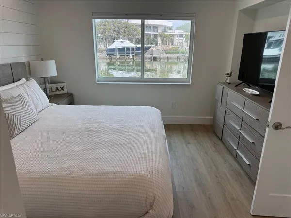 a bedroom with a bed tv and a window