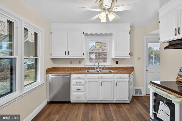 a kitchen with granite countertop a sink cabinets and wooden floor