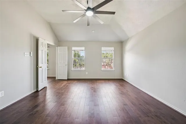 an empty room with wooden floor chandelier fan and windows