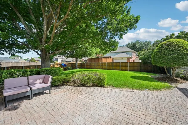 a view of a backyard with couches plants and large trees