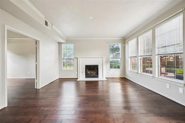 an empty room with wooden floor fireplace and windows