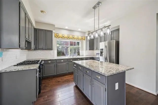 a kitchen with kitchen island granite countertop a sink stove and refrigerator