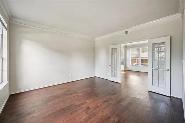 a view of an empty room with wooden floor and windows