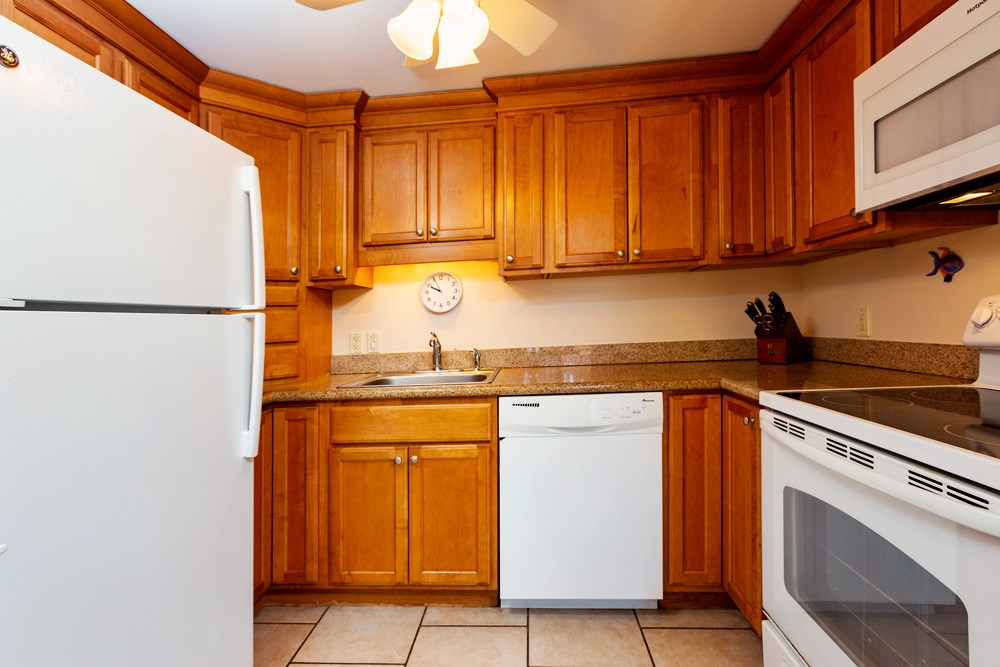 115 North Kihei Road, Unit B1 Kihei, HI 96753 - Photo 9 of 29 a kitchen with stainless steel appliances granite countertop a refrigerator sink and cabinets