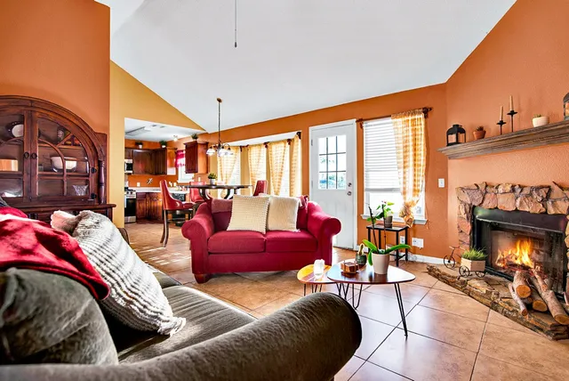 a living room with furniture a fireplace and large windows