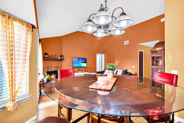 a view of a dining room with furniture a chandelier and large windows