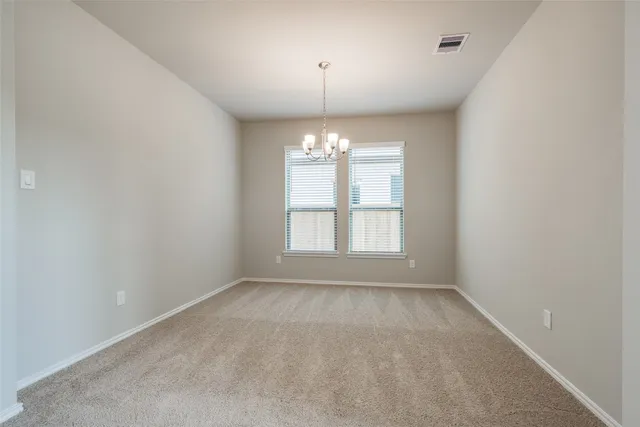an empty room with chandelier fan and windows