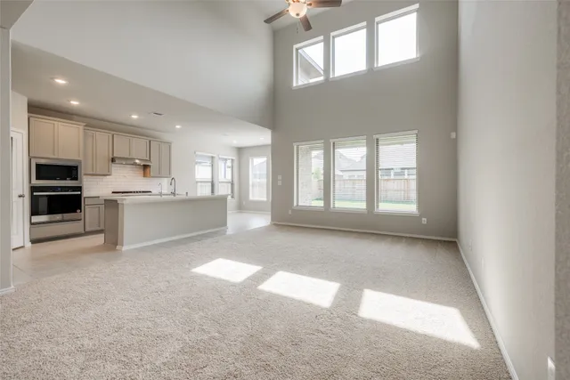 a view of an empty room with kitchen and window