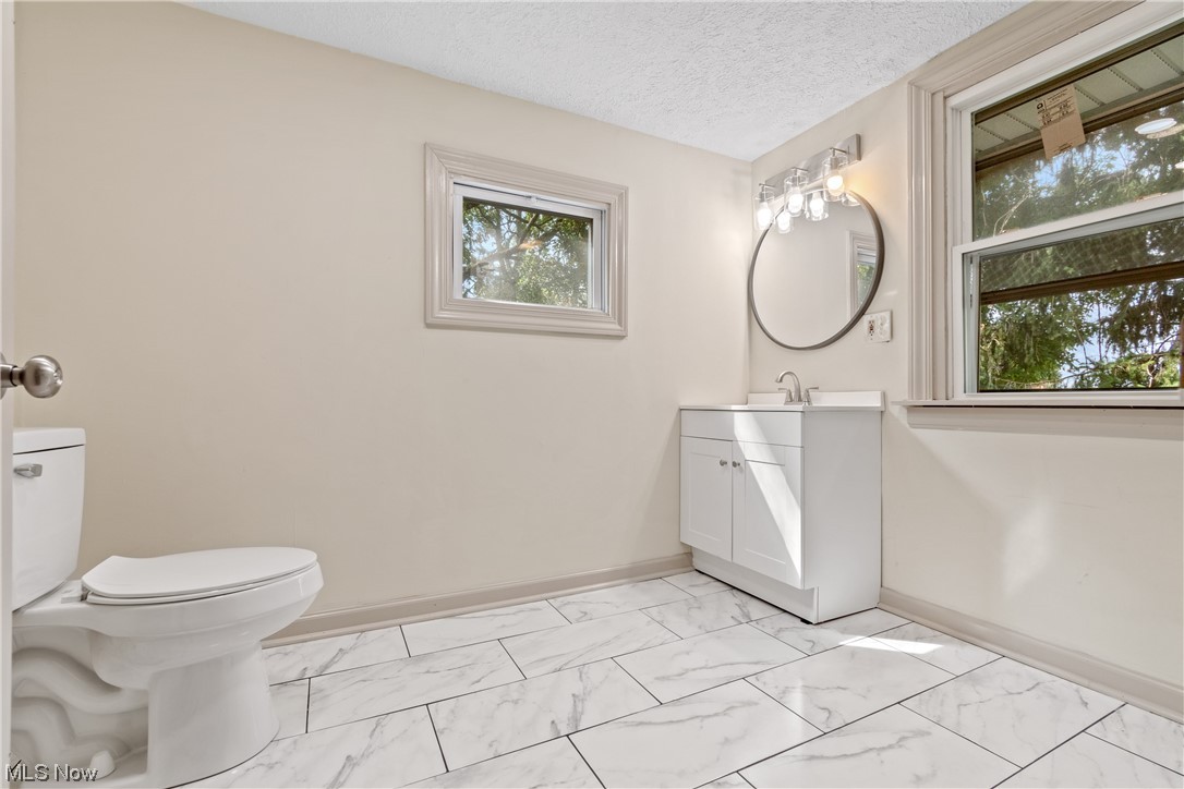 1474 Hampton Road Akron, OH 44305 - Photo 16 of 27 Bathroom featuring a textured ceiling, a wealth of natural light, mirror, vanity, and light tile flooring
