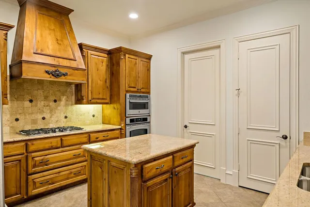 a kitchen that has a kitchen island wooden cabinets and stainless steel appliances