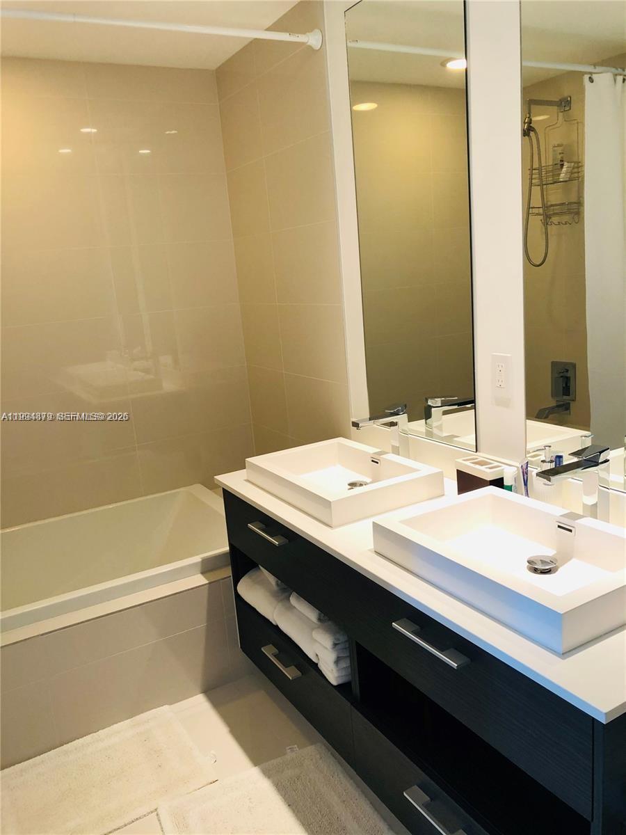 45 Southwest 9th Street, Unit 2004 Miami, FL 33130 - Photo 14 of 28 a bathroom with a sink a large mirror and a bathtub