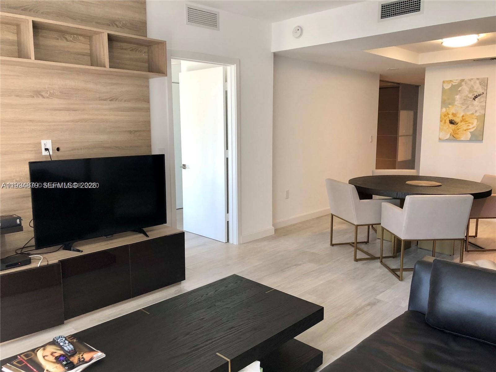45 Southwest 9th Street, Unit 2004 Miami, FL 33130 - Photo 5 of 28 a living room with furniture and a flat screen tv