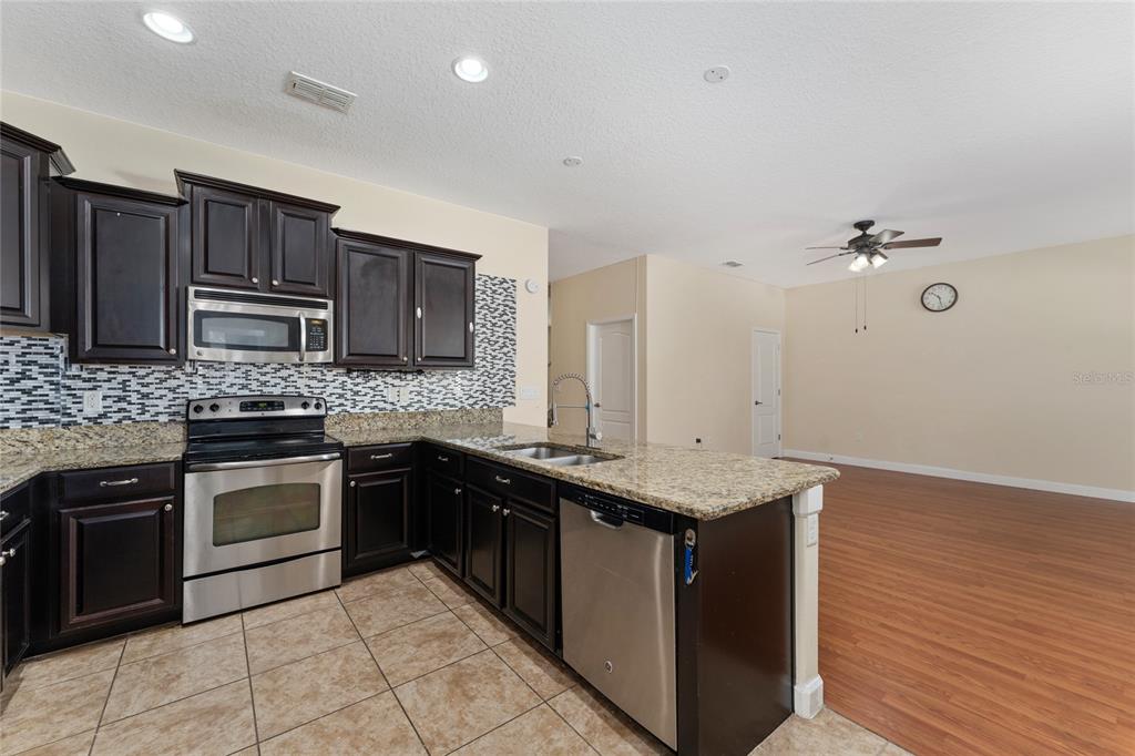 1355 Vasey Road Apopka, FL 32703 - Photo 21 of 41 a kitchen with stainless steel appliances granite countertop a sink stove and cabinets