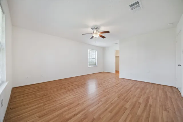 a view of empty room with wooden floor and fan